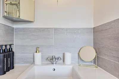 a white sink in a bathroom with a mirror at Premium 5-Bed Home, Garden, Parking & High-Speed Wi-Fi in Nevendon