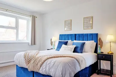 a bedroom with a blue bed and a window at Premium 5-Bed Home, Garden, Parking & High-Speed Wi-Fi in Nevendon