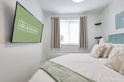 a bedroom with a bed with a green sign on the wall at Premium 5-Bed Home, Garden, Parking & High-Speed Wi-Fi in Nevendon