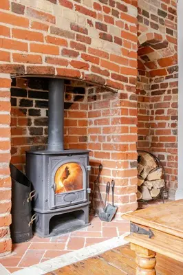 a brick fireplace with a stove in a room at Charming Georgian flint cottage in Bury Saint Edmunds