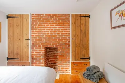 a bedroom with a brick fireplace and a bed at Charming Georgian flint cottage in Bury Saint Edmunds