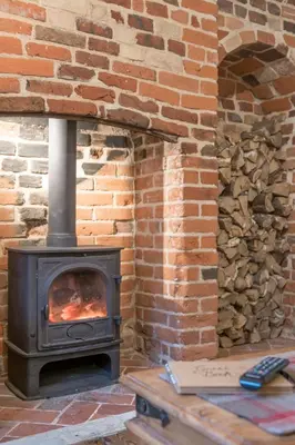 a brick fireplace with a stove in a room at Charming Georgian flint cottage in Bury Saint Edmunds