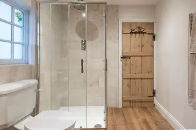a shower with a glass door in a bathroom at Charming Georgian flint cottage in Bury Saint Edmunds