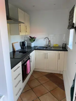 a kitchen with white cabinets and black counter tops at Entire flat 2 to 4 pers 1 bed 1 bath disabled access for limited disability