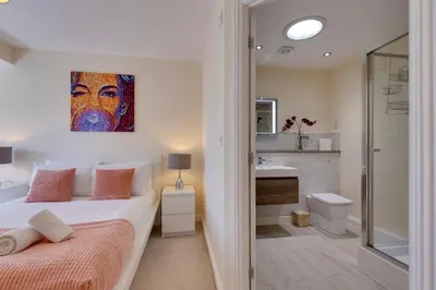 a bedroom with a king sized bed and a bathroom at Modern House with Free Parking & Superfast WiFi in Cambridge