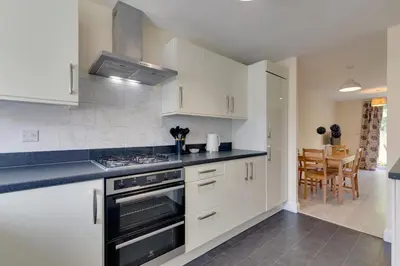 a kitchen with white cabinets and a stove top oven at Modern House with Free Parking & Superfast WiFi in Cambridge