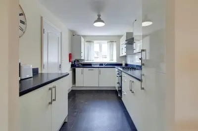 a kitchen with white cabinets and black counter tops at Modern House with Free Parking & Superfast WiFi in Cambridge