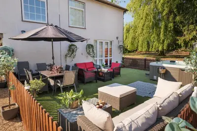 an outdoor patio with a couch and an umbrella at Sampford Hideaway Retreat in Great Sampford