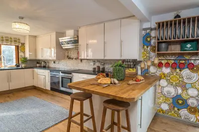 a kitchen with white cabinets and a wooden table at Sampford Hideaway Retreat in Great Sampford
