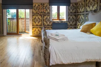 a bedroom with a white bed with a wooden floor at Sampford Hideaway Retreat in Great Sampford