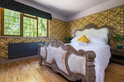 a bedroom with a large bed and yellow wallpaper at Sampford Hideaway Retreat in Great Sampford