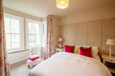 a bedroom with a bed and a chair and a window at 3 bed Victorian terrace 10mins walk from Colchester city centre in Colchester