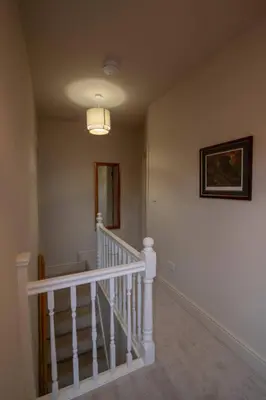 a hallway with a white staircase with a picture on the wall at 3 bed Victorian terrace 10mins walk from Colchester city centre in Colchester