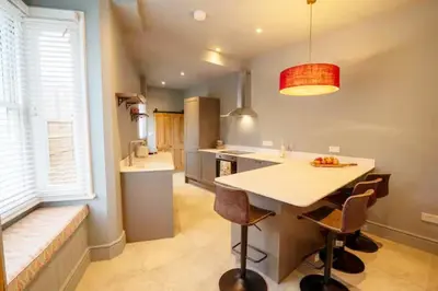 a kitchen with a island with chairs and a table at 3 bed Victorian terrace 10mins walk from Colchester city centre in Colchester