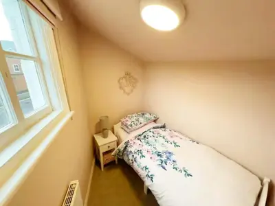 a small bedroom with a bed and a window at 3 bed Victorian terrace 10mins walk from Colchester city centre in Colchester
