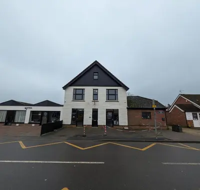 a white building with a black roof in a parking lot at Digby House flat 1 in West Mersea