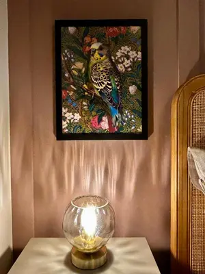 a lamp on a table with a picture of a bird at Daisy Cottage - Framlingham in Framlingham