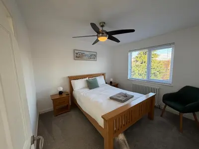 a bedroom with a bed with a ceiling fan and a chair at City Centre, En-Suite, 3 Doubles 1 Single, 2 Car Parking in Colchester