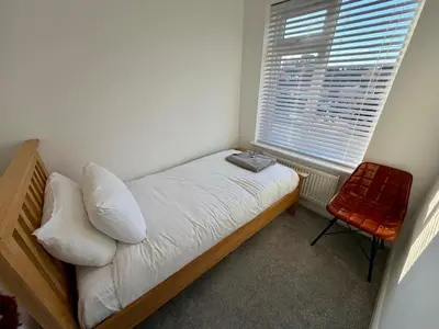 a bedroom with a bed and a window and a chair at City Centre, En-Suite, 3 Doubles 1 Single, 2 Car Parking in Colchester