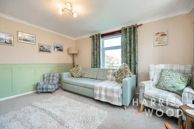 a living room with a blue couch and two chairs at Vine Cottage in Chelmondiston