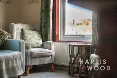 a living room with two chairs and a window at Vine Cottage in Chelmondiston