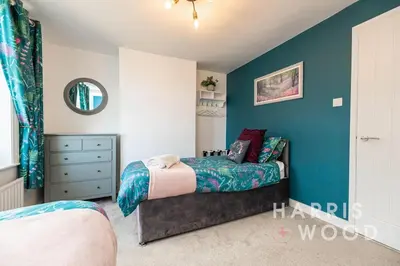 a bedroom with a bed and a blue wall at Vine Cottage in Chelmondiston