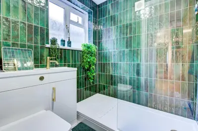 a green tiled bathroom with a tub and a sink at Cottage in the centre in Colchester