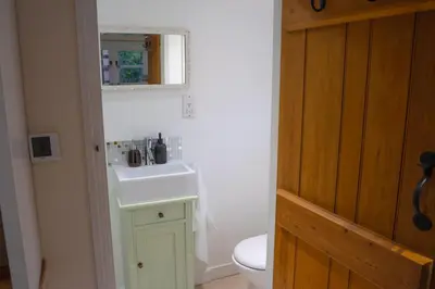a bathroom with a white sink and a toilet at The Cotswold Luxe Cottage in Framlingham