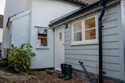 a white house with a door and two windows at The Cotswold Luxe Cottage in Framlingham