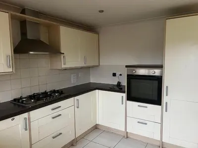 a kitchen with white cabinets and a stove top oven at Chartsworth 4 Bedrooms Spacious House in Harold Wood