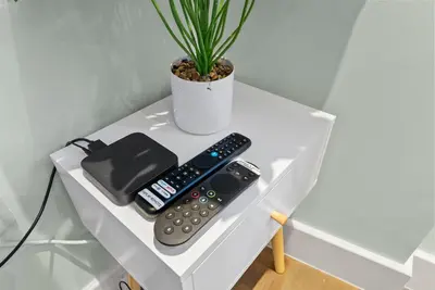 a table with two remote controls and a potted plant at Modern, Quiet & Cozy Flat in Central Chelmsford - F7 in Chelmsford