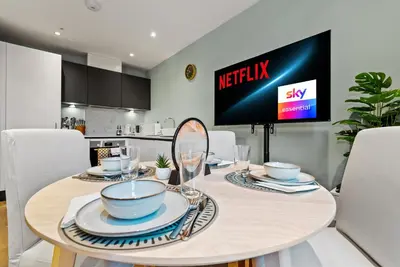 a dining room table with a television in a kitchen at Modern, Quiet & Cozy Flat in Central Chelmsford - F7 in Chelmsford
