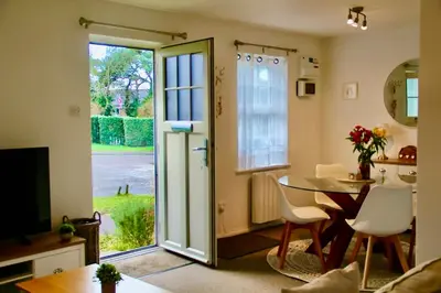 a living room with a table and a glass door at Seaside Luxury Cottage Aldeburgh in Aldeburgh