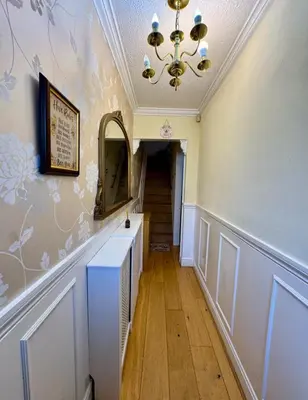 a hallway with a mirror and a chandelier and stairs at Three Bees in Hythe