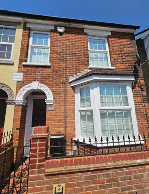 a brick house with a window and a fence at Three Bees in Hythe