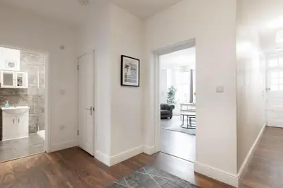 a white room with a hallway with a sink and a mirror at The Regency | Seafront Lux Apartments! in Southend-on-Sea