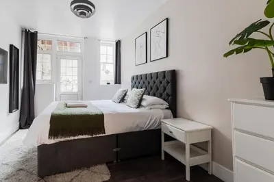 a bedroom with a large bed with a green blanket at The Regency | Seafront Lux Apartments! in Southend-on-Sea