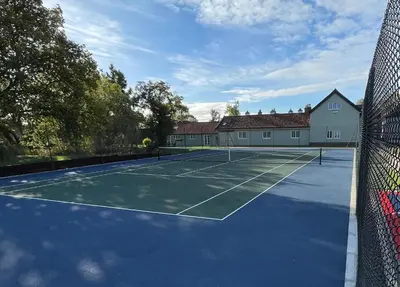 a tennis court in front of a house at Martley Hall Estate by Group Retreats in Woodbridge