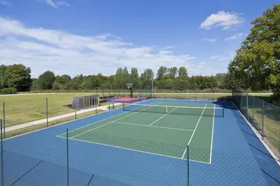 a tennis court with a net on top of it at Martley Hall Estate by Group Retreats in Woodbridge