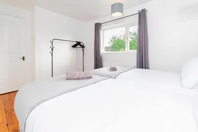 a white bedroom with a large bed and a window at Beautiful 3 Bedroom Home with Parking & Garden in Colchester