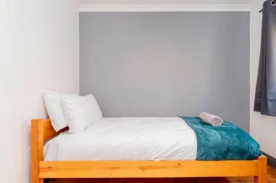 a small bedroom with a wooden bed with white sheets at Beautiful 3 Bedroom Home with Parking & Garden in Colchester