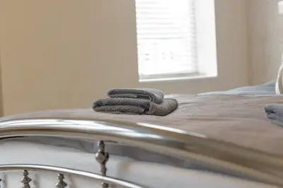 two towels are sitting on top of a bed at Cambridge Charming 2 Bedroom Home I Rustic Floors & Office I Parking in Milton