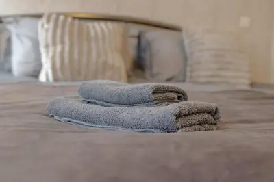 a pile of towels sitting on top of a bed at Cambridge Charming 2 Bedroom Home I Rustic Floors & Office I Parking in Milton