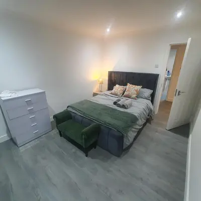 a bedroom with a bed and a dresser with a green bedspread at 3 Bedroom House Ingatestone in Freyerning
