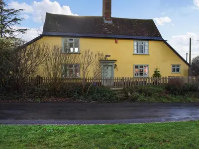 a yellow house with a fence in front of it at Hill House in Colchester
