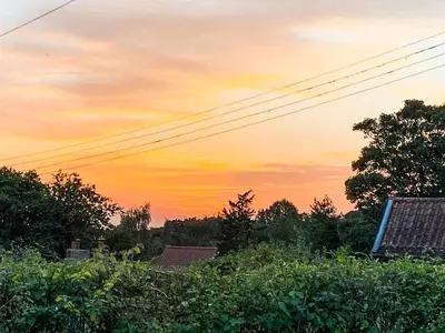 a sunset in the sky over houses and trees at Hill House in Colchester