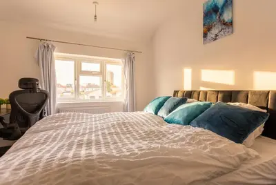 a bedroom with a large bed with a window at Spacious 3-Bed Home for 8 | Free Parking & Garden in Havering atte Bower