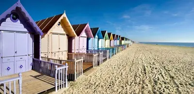 a row of colorful beach huts on the beach at Digby house flat 2 in West Mersea