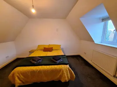 a bedroom with a bed with yellow sheets and a window at Modern home close to amenities and transport links in Wymondham