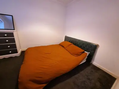 a bedroom with a bed with an orange pillow and a dresser at Modern home close to amenities and transport links in Wymondham
